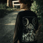 Back detail of Still Cursed long sleeve tee – inverted occult symbol and smoky blackwork illustration on organic heavy cotton